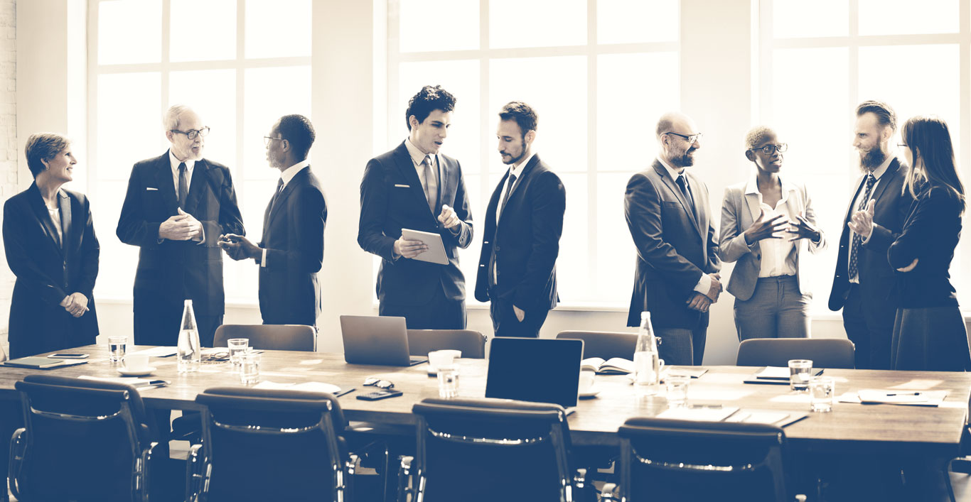 Business Professionals (Advisors) in a meeting room standing and networking with eachother