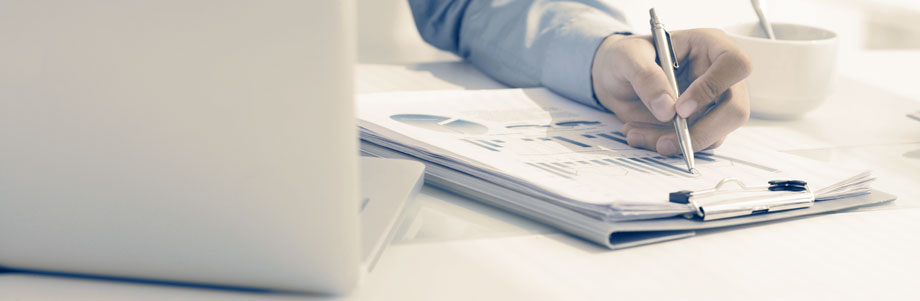 Business man making notes on a pad and using a laptop